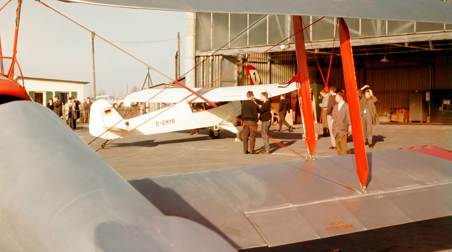 Neugier: Die neue Piper PA-18 vor der Landeshalle, umringt von Vereinsmitgliedern. Im Vordergrund eine der beiden Tiger Moths, die durch das neue Schleppflugzeug ersetzt werden. (Foto: Günther Lücker)
