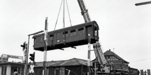 Trennung des wohnlichen Waggonaufbaus vom fahrbaren Untersatz. Letzterer hat zwar nur noch Schrottwert, aber der Schrott ist einiges Wert und dient der Kompensation für die Dienste des Kranverleihs (Foto: LVA, SW-Original mit KI-Unterstützung restauriert)